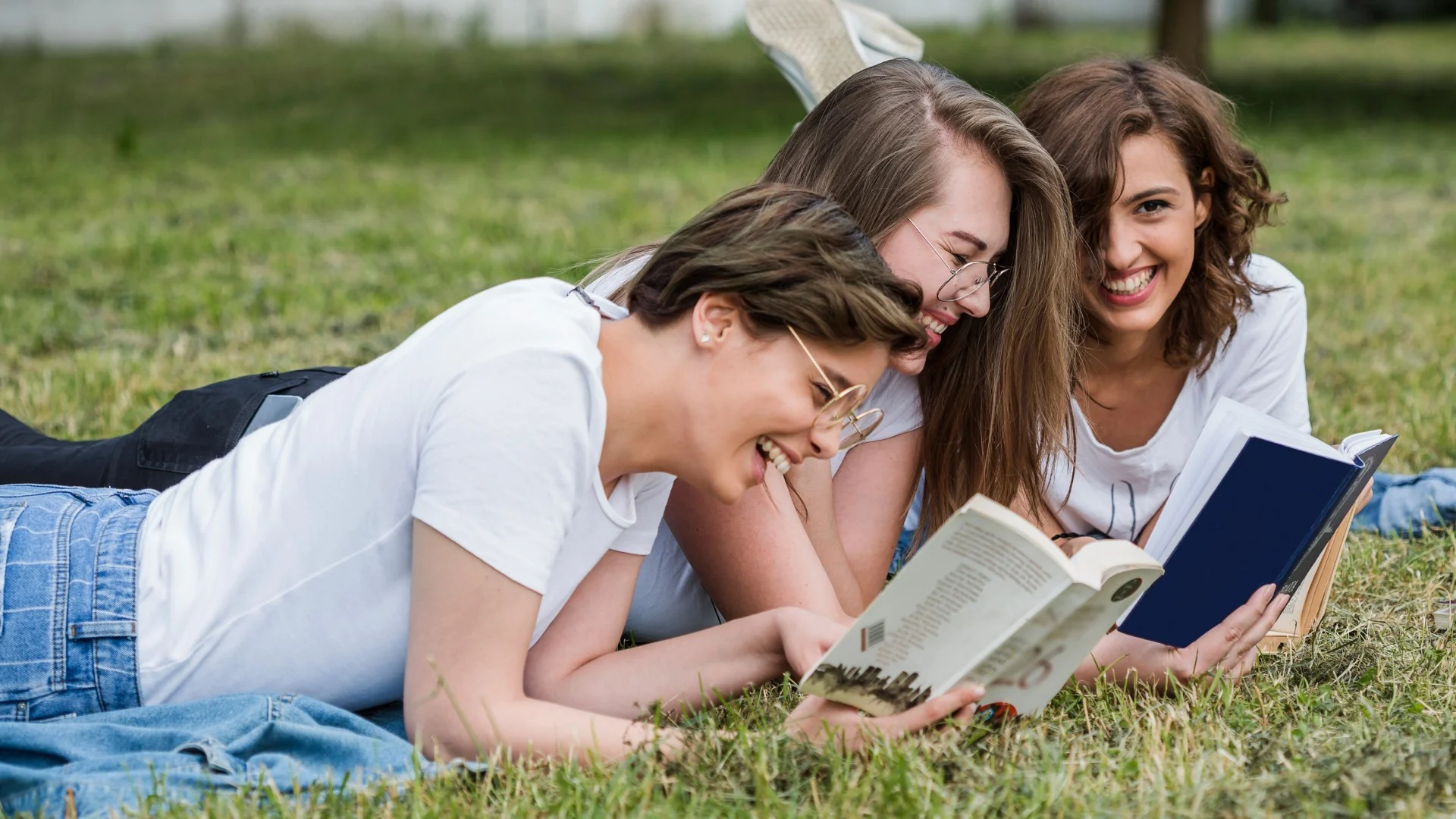 young-friends-reading-lying-park-lawn
